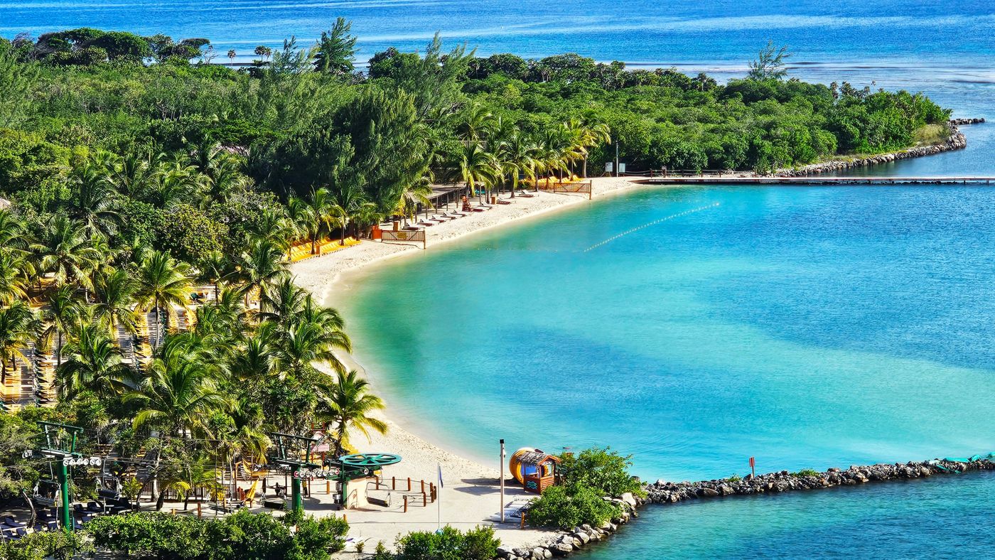 Curving white-sand beach lined with palm trees and clear turquoise water