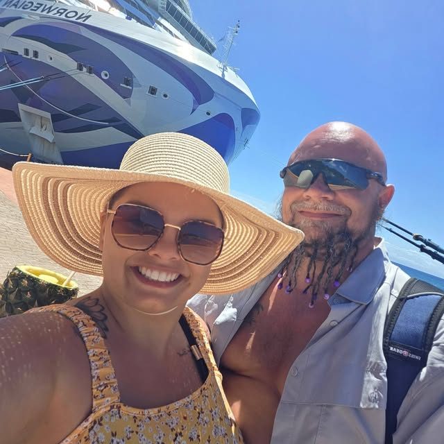 A couple in front of a Norwegian cruise ship