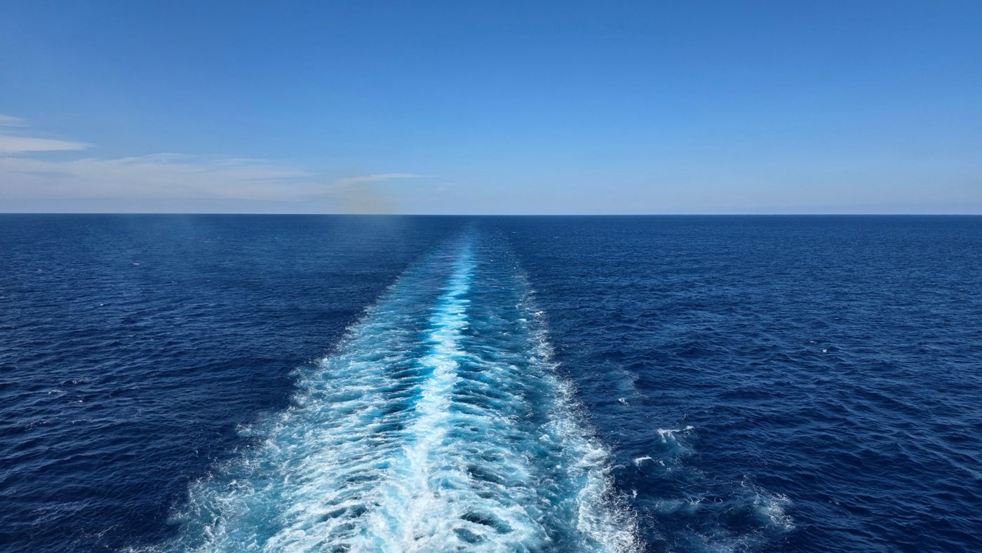 A ship's wake trailing across deep blue open ocean